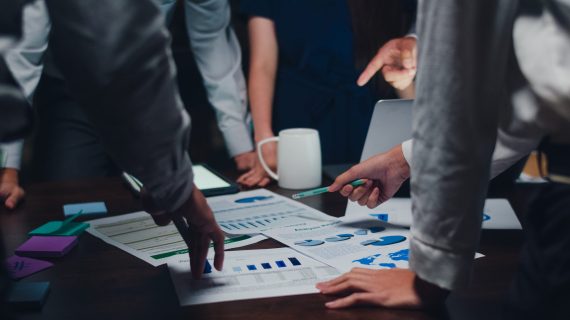 Millennial Asia businessmen and businesswomen meeting brainstorming ideas about new paperwork project colleagues working together planning success strategy enjoy teamwork in small modern night office.